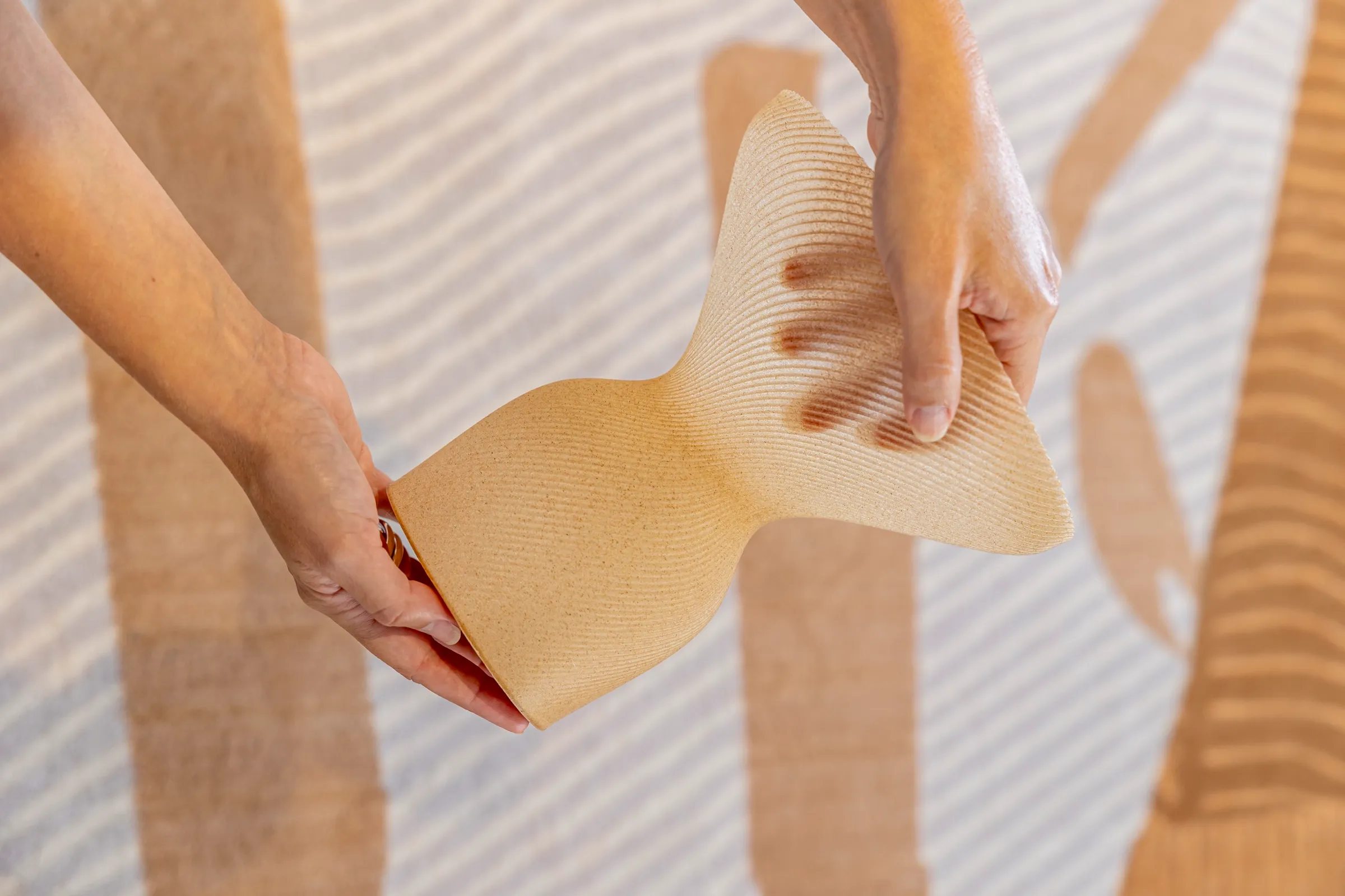 Deux mains présentent un vase imprimé et sa texture végétale nervurée